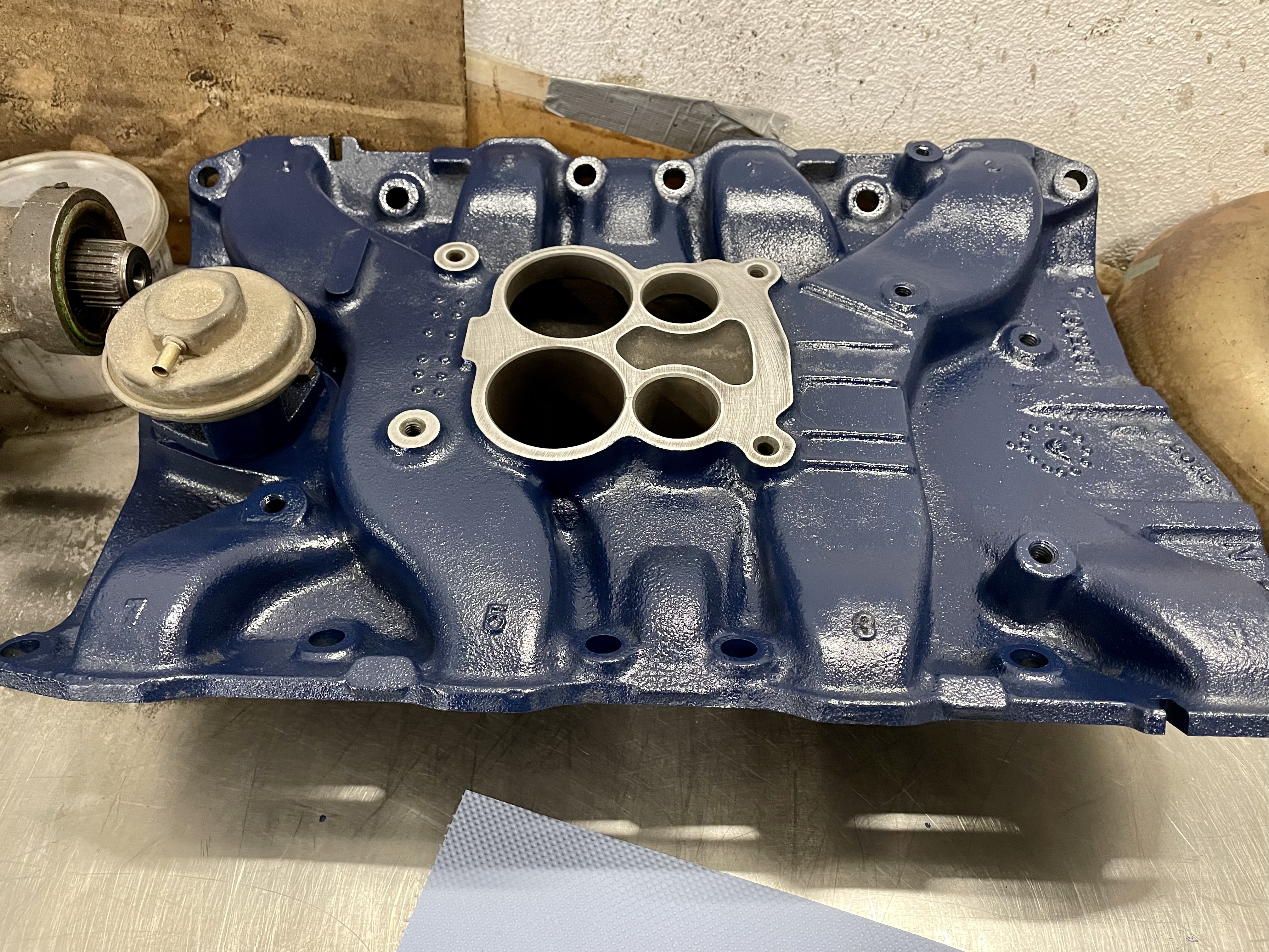 Blaue Ansaugbrücke (Motorblock-Teil) für klassische US-Fahrzeuge wie Cadillac oder Lincoln (Baujahre 1956-1979) mit Metallflansch für Vergaser, typisch für Reparaturen in der Oldtimer Profi-Werkstatt.
