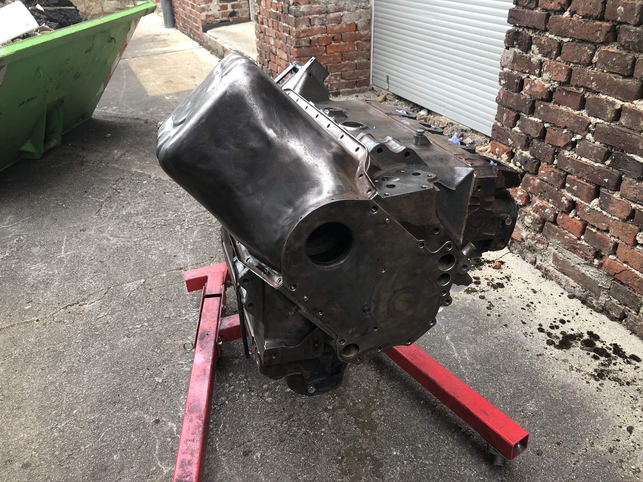 Ein klassischer Automotor auf einem roten Ständer in einer Werkstatt, repräsentativ für die Reparatur und Pflege von Oldtimern wie Cadillac oder Lincoln.