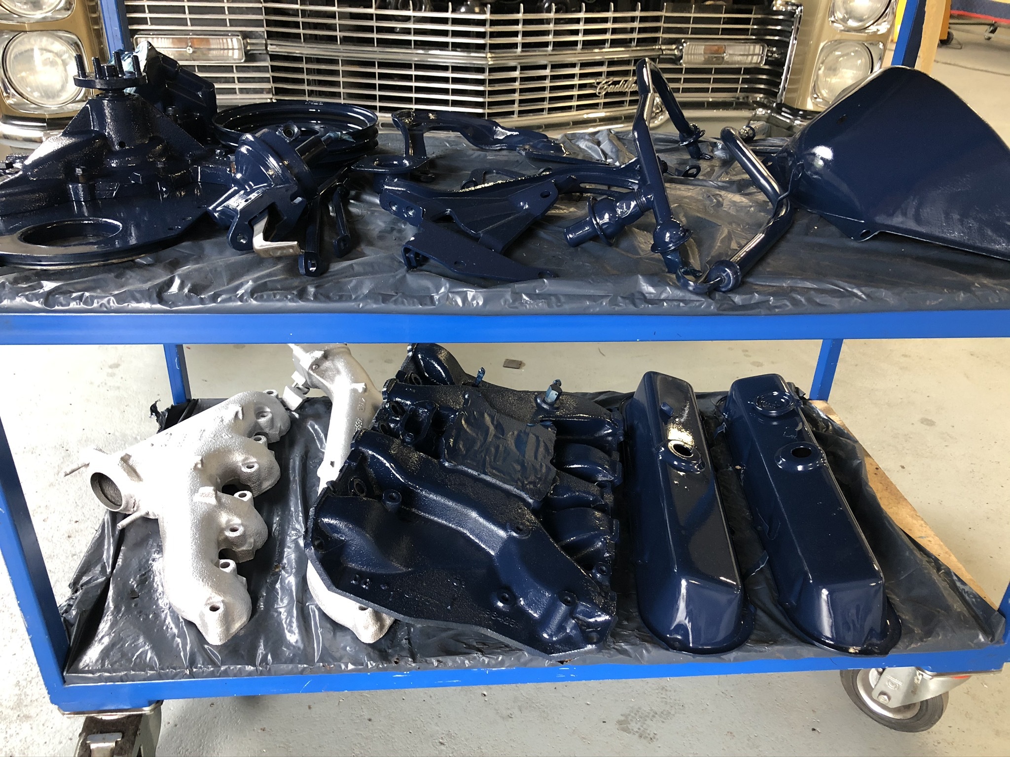 Gelackte Ersatzteile für klassische US-Fahrzeuge (z. B. Cadillac, Lincoln) auf einem Werkstattwagen – Vorbereitung für die Restauration in der spezialisierten Oldtimer-Werkstatt Oldtimer Profi.
