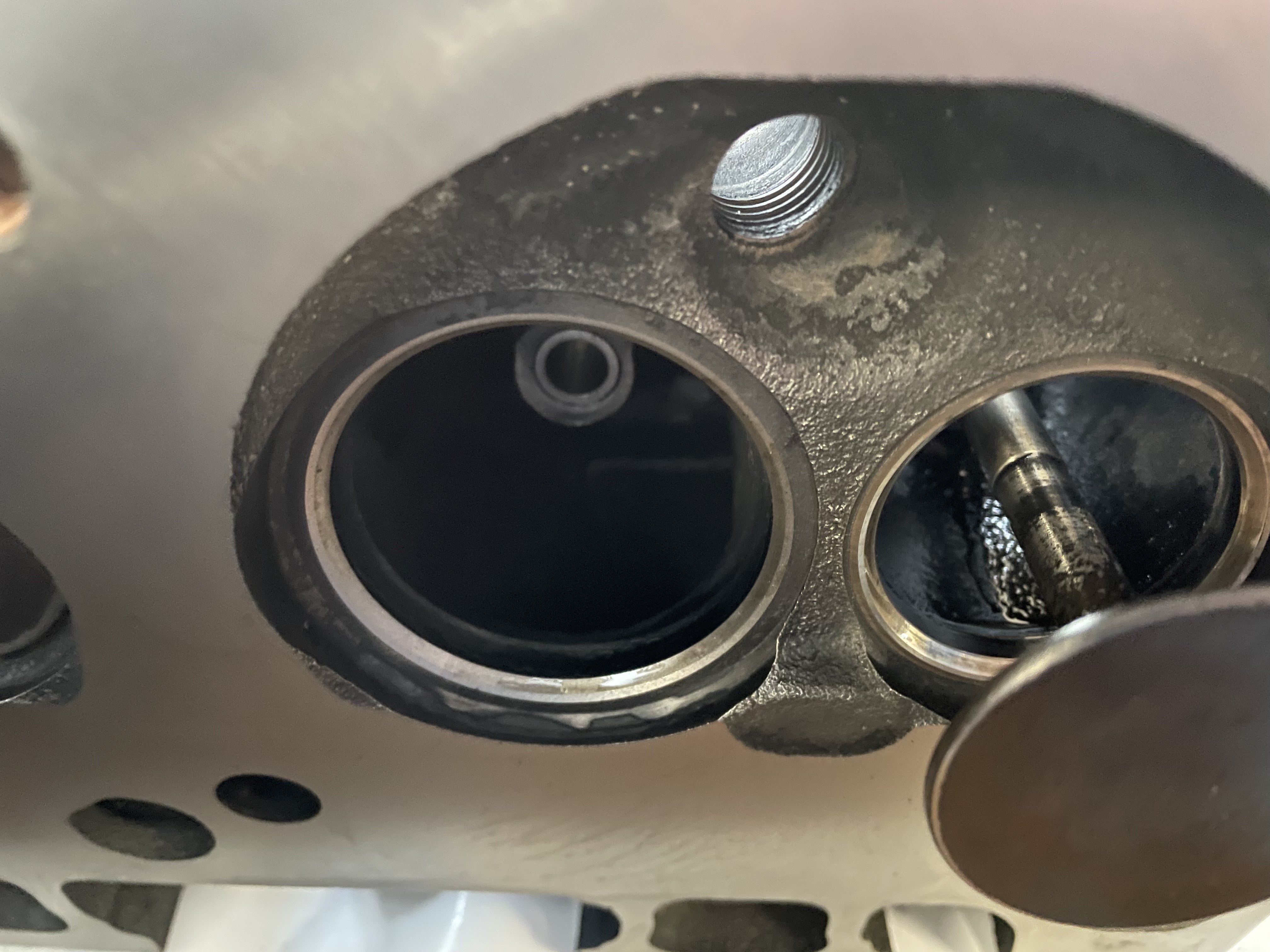 Nahaufnahme eines abgenutzten Zylinderkopfs aus einem klassischen US-Fahrzeug (Cadillac/Lincoln, 1956-1979) mit sichtbarem Ventil und Gewindebohrung – typisches Bauteil für Reparaturen und Wartungen in der Oldtimer Profi Werkstatt.